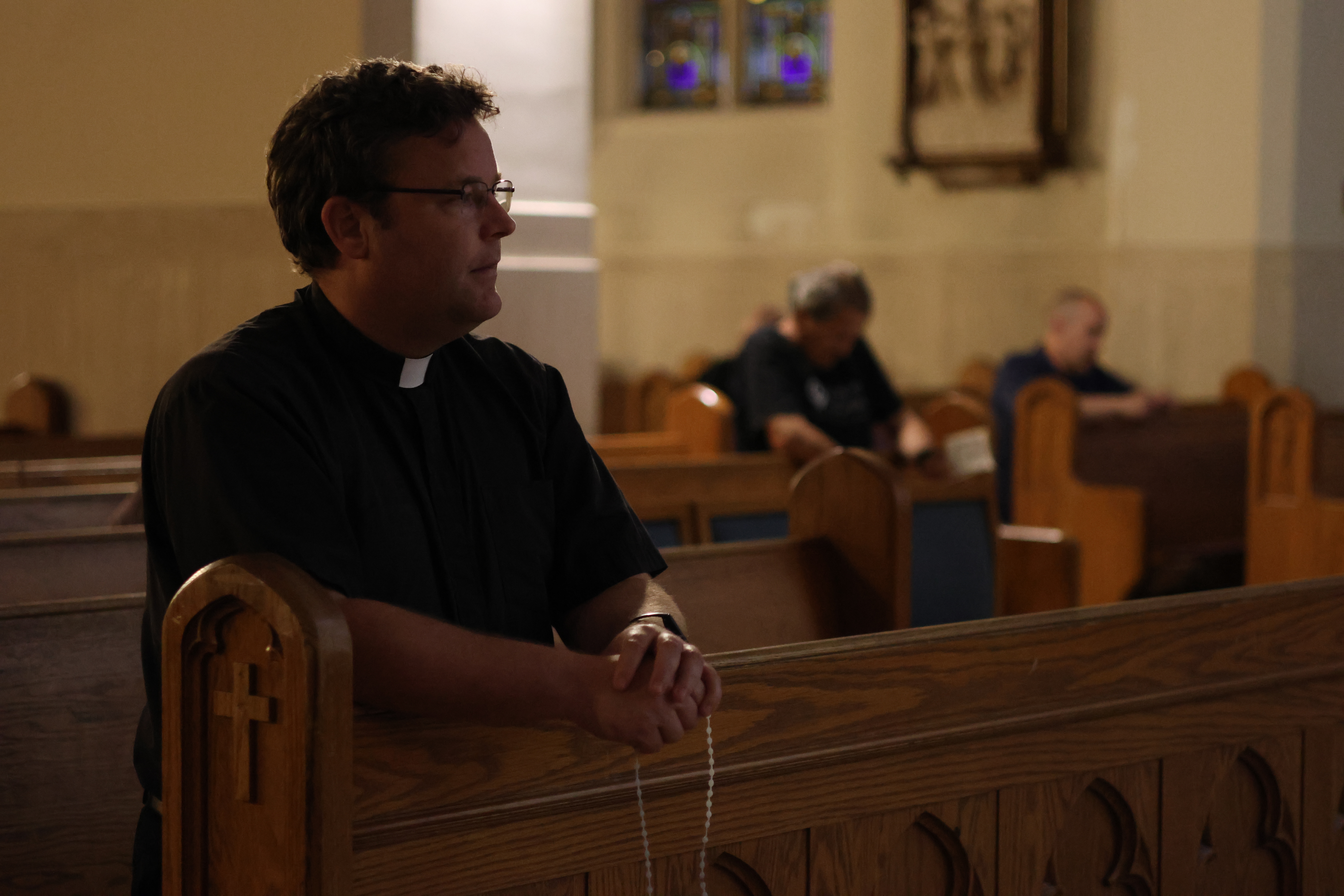 Photo of Fr Knox kneeling and praying the Rosary with the men, in front of the Saint Joseph chapel at the Cathedral of the immaculate conception