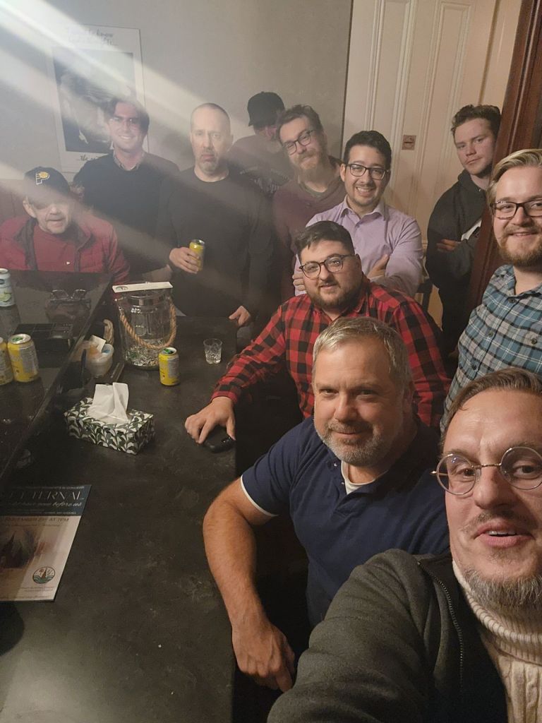 Photo of the men together gathering around the bar